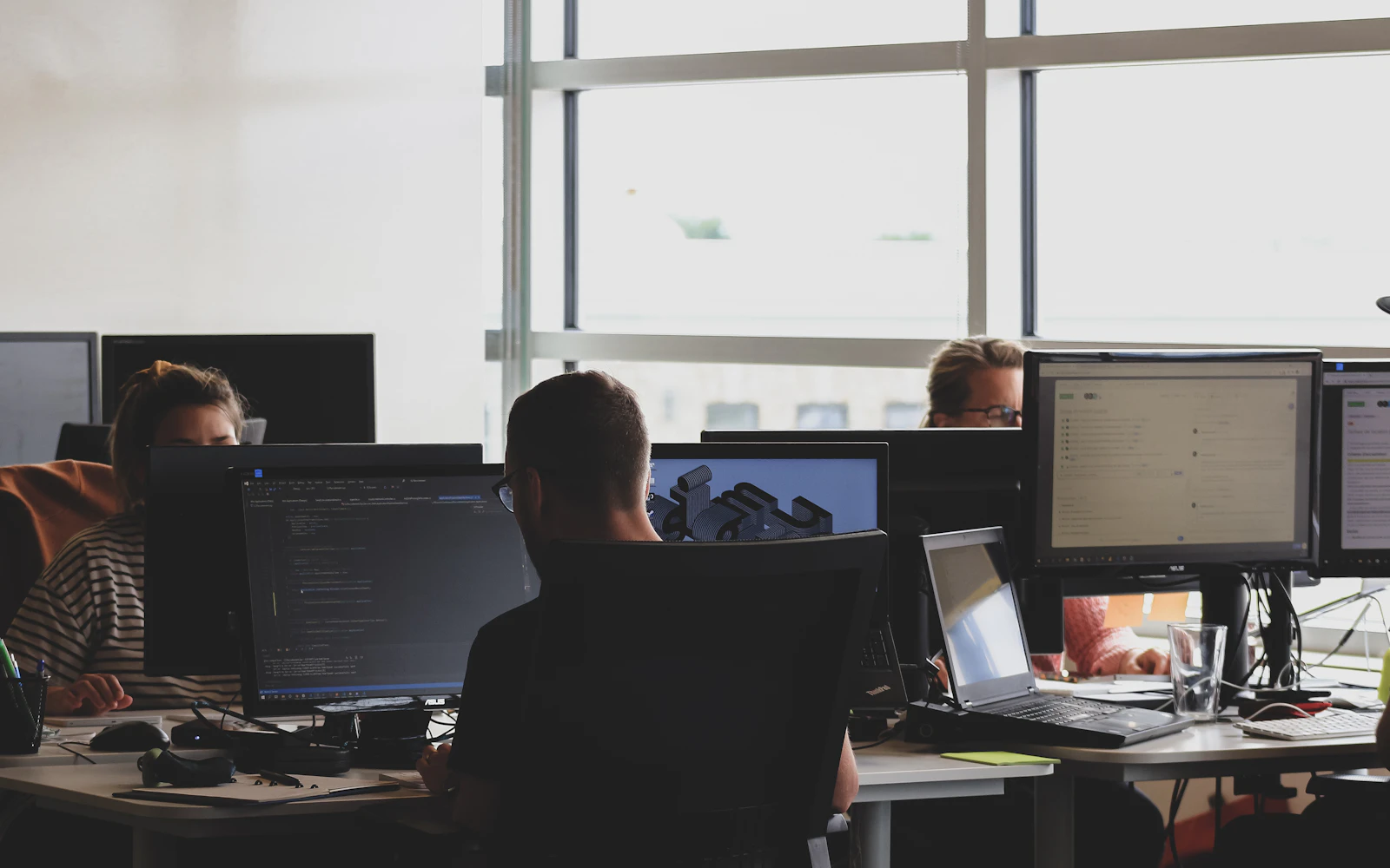 Technology team working across multiple monitors in a shared office